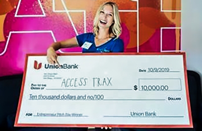 Woman holding large $10,000 check to Access Trax