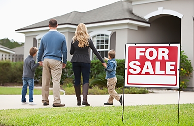 Family standing in front of a home for sale